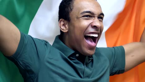 irish fan celebrating while holding the flag of ireland in slow motion