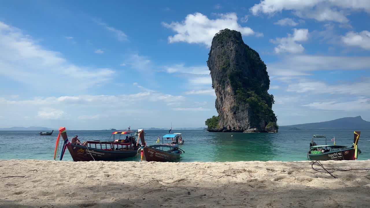 Tre barche a coda lunga ondeggiano dolcemente nel Mare delle Andamane, nella regione di Krabi.