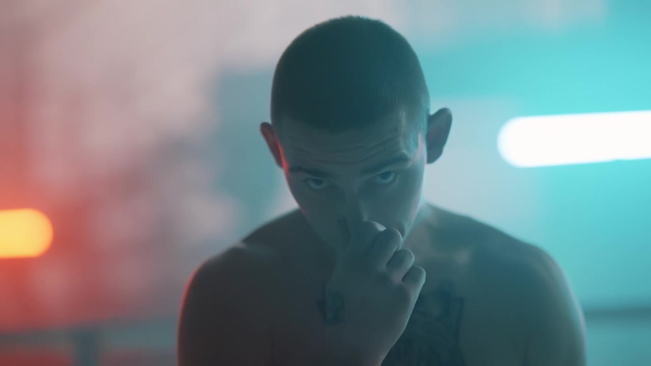 Ritratto di un giovane uomo serio con tatuaggio sotto un'illuminazione al neon suggestiva.