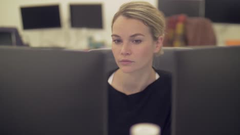 A-female-employee-is-working-with-two-computer-monitors-and-is-looking-around-in-the-office