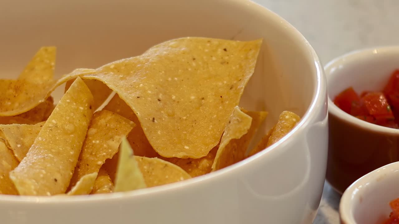 Una ciotola di tortilla chips accanto a una piccola ciotola di salsa, pronta per essere servita