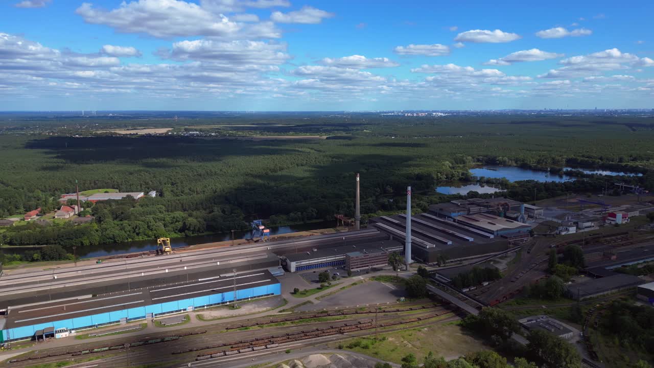 Hennigsdorf steel factory with chimneys, warehouses, railway, near river and forest in summer. Best aerial view flight panorama overview drone