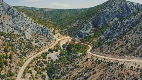 Road-heading-through-desert-valley-alongside-rocky-hills