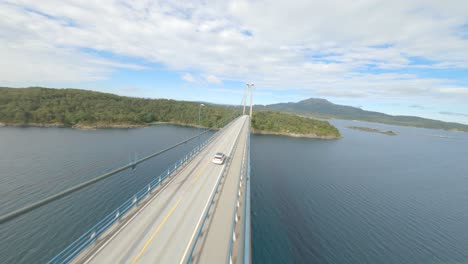 dangerous closeby flying fpv drone near suspension bridge while white car driving on