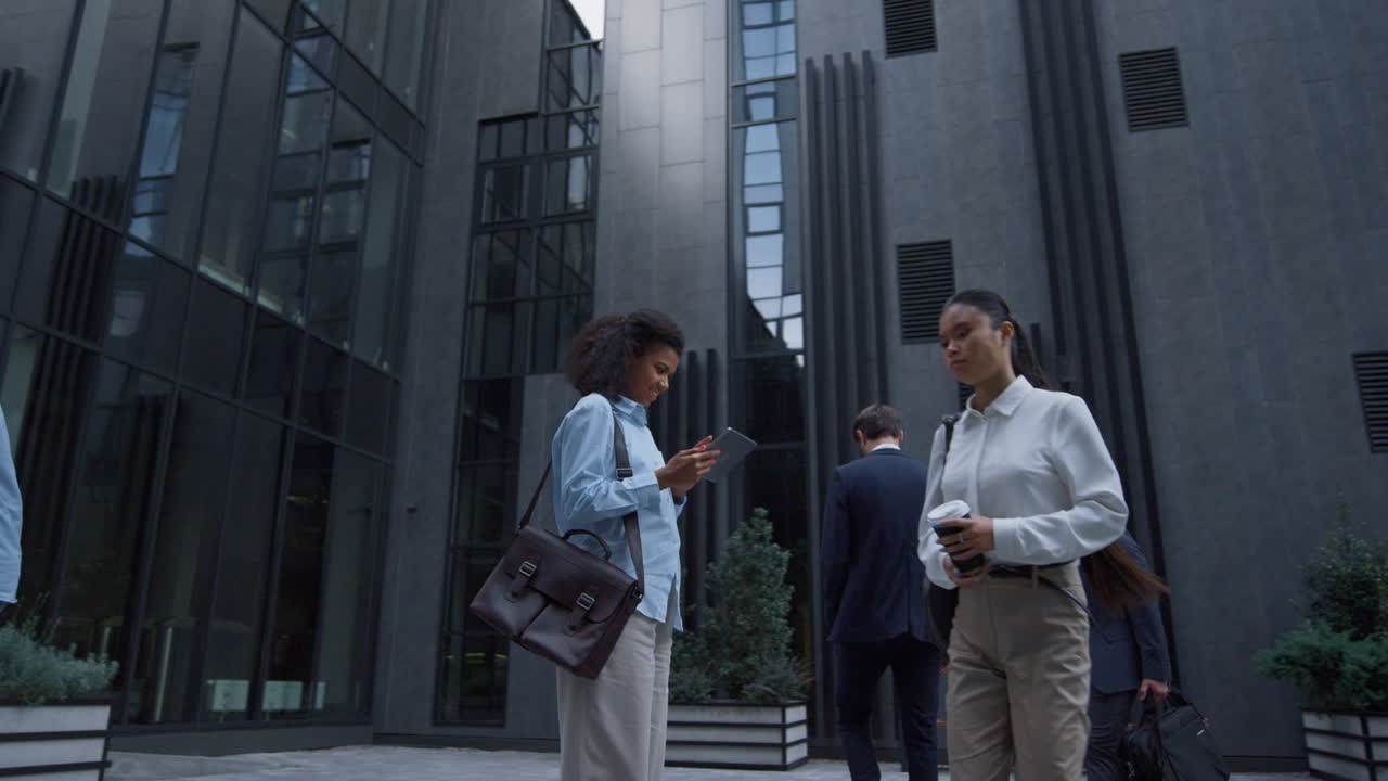 un gestore sorridente che lavora su un tablet in piedi in un moderno edificio per uffici.