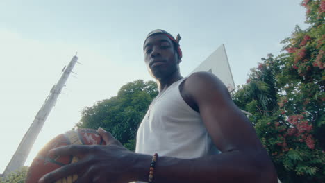 young black man posing with basketball on outdoor court