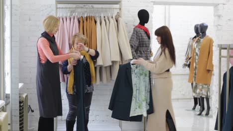 a sales consultant in a clothing store serves two elderly women by showing them clothes. attentive and courteous service