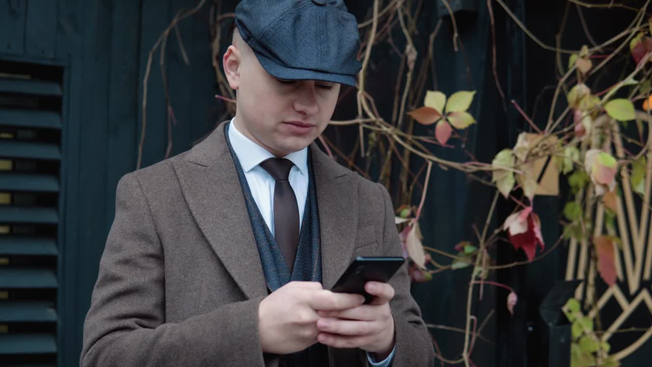 Giovane uomo d'affari elegante che usa lo smartphone per strada. Ritratto di un bell'uomo che parla al telefono all'aperto