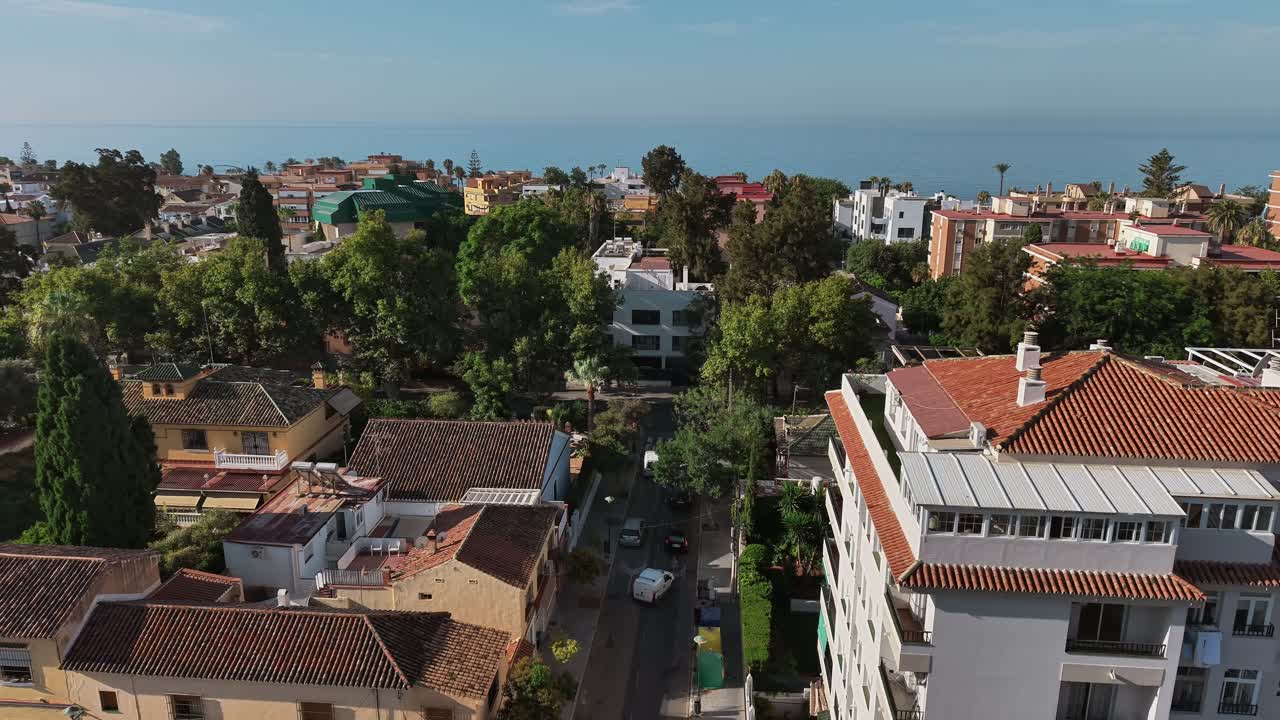 Panoramic aerial view of suburban neighborhood with trees and distant coastline with sea, Spain