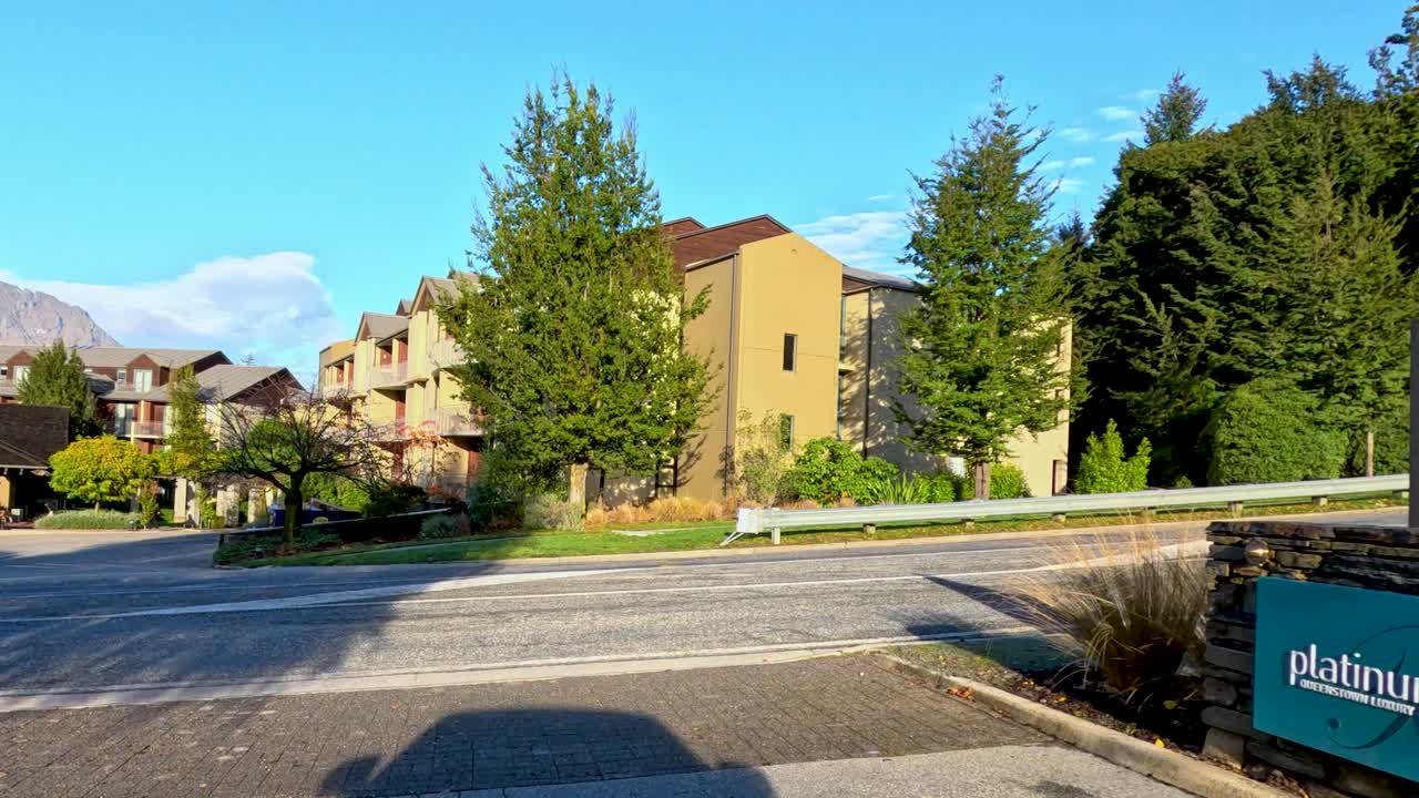 Sunny morning drive past autumn trees, suburban homes, and mountain views in Queenstown, New Zealand