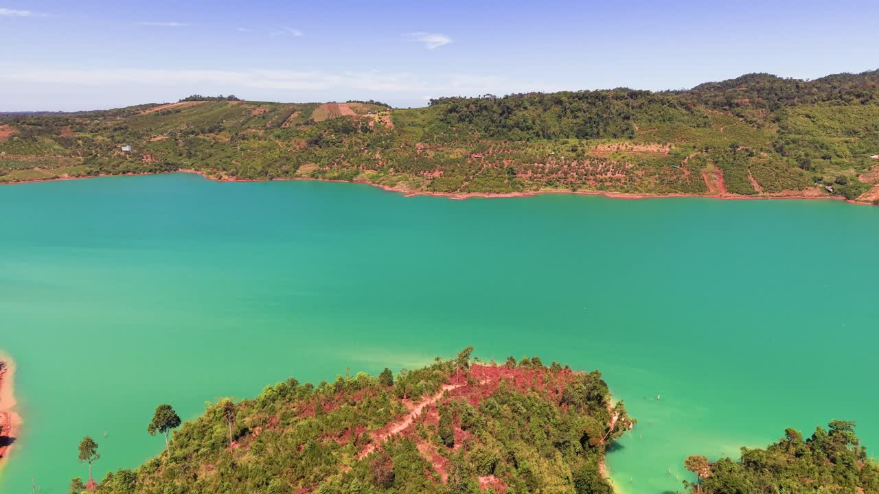 Uma vista ampla de um lago calmo em Lam Dong, Vietnã. Colinas e árvores circundantes contribuem para a beleza da paisagem em um dia ensolarado nesta área