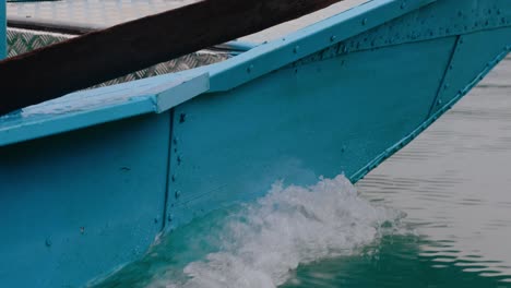 a close-up shot of a blue wooden boat gliding across a river in vietnam