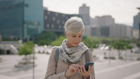 portrait of mature caucasian business woman executive reading messages using smartphone networking in sunny urban city background