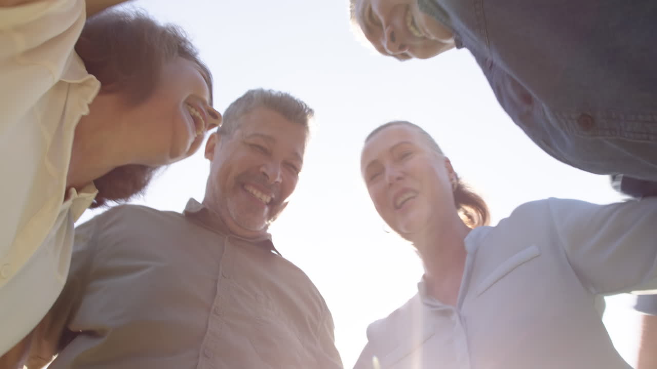 Smiling senior friends standing in circle, enjoying time together outdoors