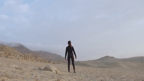 Hermosa-Mujer-Vestida-De-Negro-Desde-Atrás-En-Un-Misterioso-Desierto-Solitario-Y-Nublado