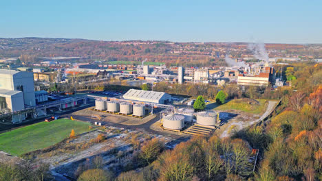 aerial footage moving towards a large industrial chemical plant, showing pipelines, metal structures, cooling towers and chemical storage