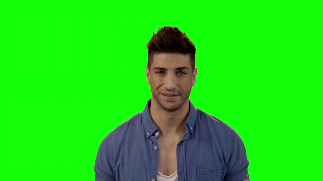 hombre sonriente de pie contra la pantalla verde