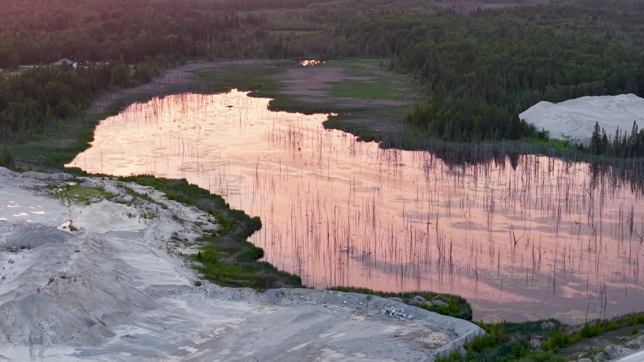 Aerial drone view of dramatic white cliffs reflecting warm sunset light above a forested shoreline