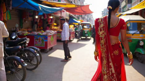 woman in red sari walking through a bustling indian street market