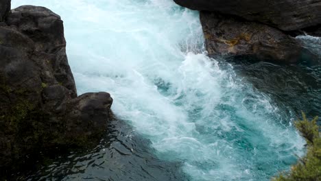 medium shot of bubbling white water at the vibrant blue huka falls in new zealand