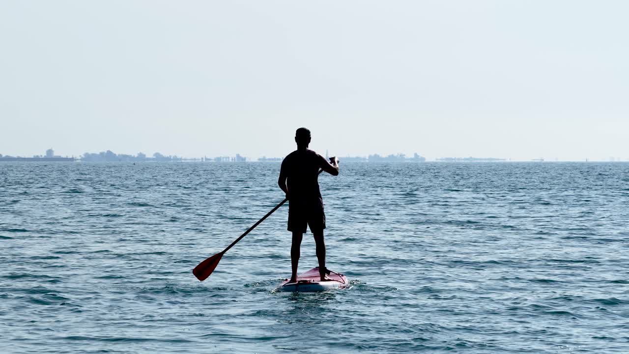 Silhouette of athlete paddle boarding on calm water