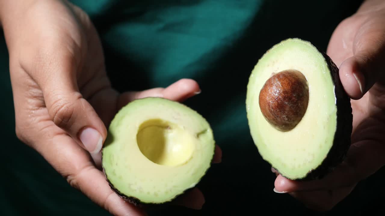 Metà di avocado tenute in mano