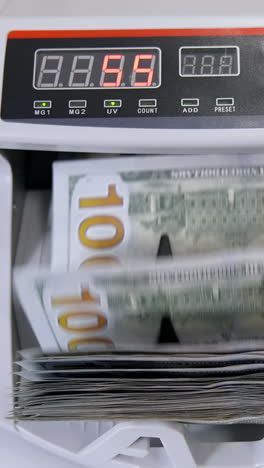 automatic money counting in the machine. electronic money machine is counting the dollar banknotes. front view. close-up. vertical video