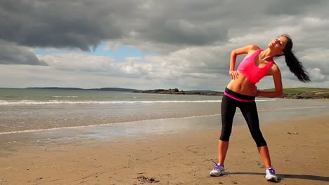 Beautiful-brunette-stretching-and-warming-up-on-the-beach