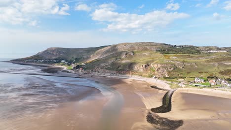 Schöne-Spiegelung-Der-Weißen-Wolken-Mit-Dem-Blauen-Himmel-Im-Langsam-Fließenden-Wasser-Bei-Ebbe-Mit-Den-Hohen-Grünen-Hügeln-Von-Wales-Im-Hintergrund