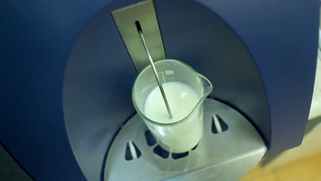 glass with milk in laboratory equipment for testing dairy products