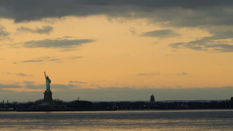 sunset over new york harbor with statue of liberty