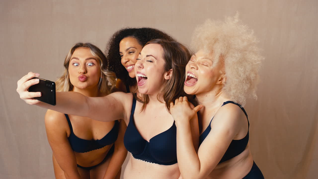 grupo de diversas amigas de cuerpo positivo en ropa interior posando para selfies en el teléfono móvil