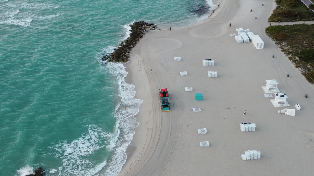 파도가 바위에 부딪히는 동안 플로리다 주 마이애미의 해변을 청소하는 트랙터의 드론 영상
