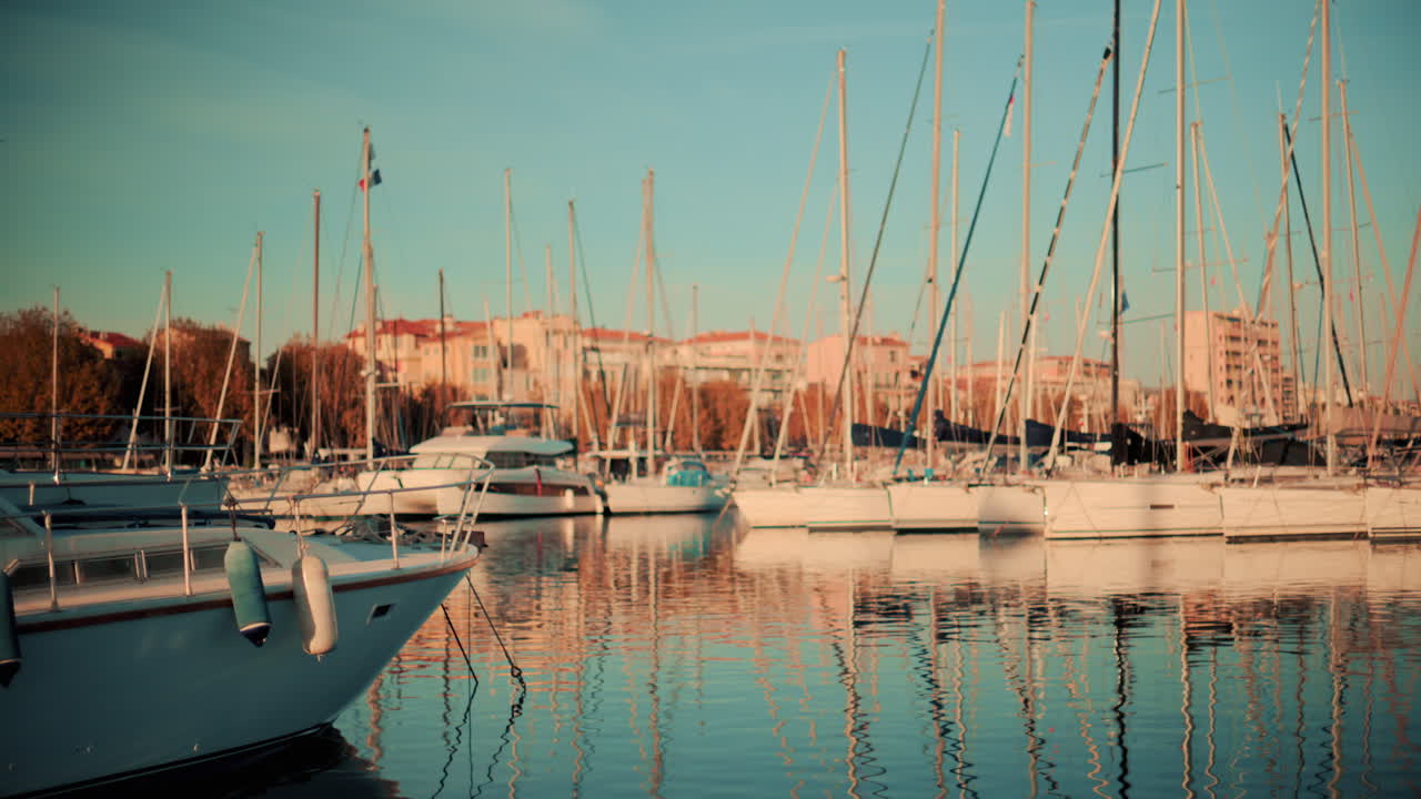 Tranquilla scena di un porticciolo turistico con yacht e barche a vela ancorate in acque calme durante l'ora d'oro