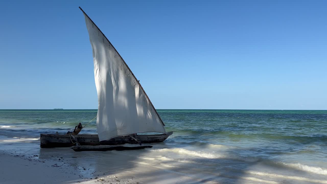 Zanzibar-strand med en traditionel dhow-sejlbåd i lavt havvand. Tanzania