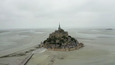 mont-saint-michel-drone-camera-going-forward,-there-are-many-toristo-coming-to-see-the-palace