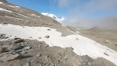 fpv drone follows two mountain bikers descending steep, exposed alpine trails above saas-grund and saas-fee on a clear bluebird summer day, showcasing epic terrain and speed