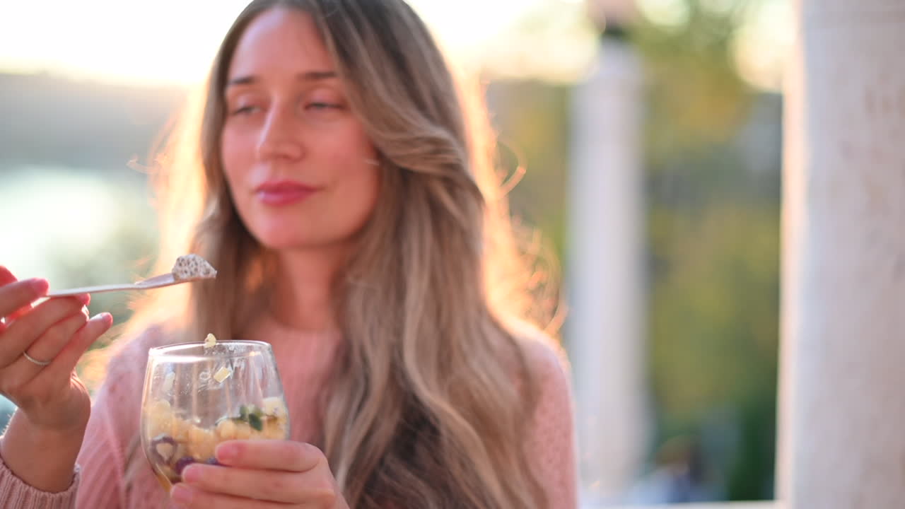 Woman eating a fruit salad with chia seeds in a park at the sunset