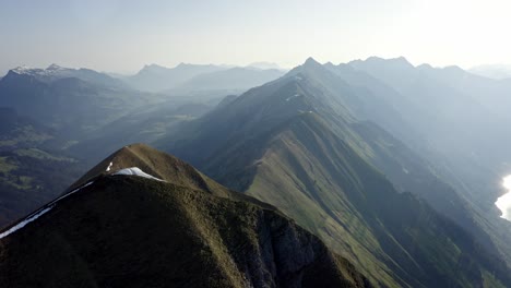 Beautiful-endless-ridge-top-amongst-huge-mountains-and-above-a-green-valley-with-a-blue-lake