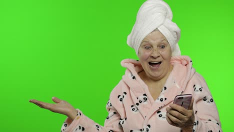 Elderly-grandmother-in-bathrobe.-Old-woman-with-smartphone-pointing-at-something