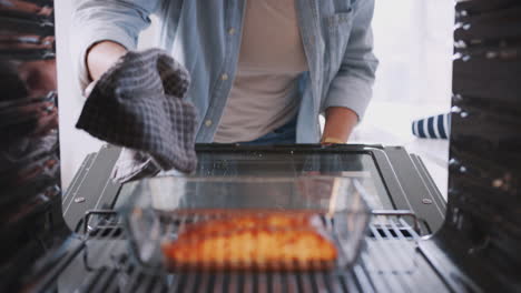 Blick-Aus-Dem-Inneren-Des-Ofens,-Während-Eine-Frau-Im-Ofen-Gebackenen-Lachs-Kocht