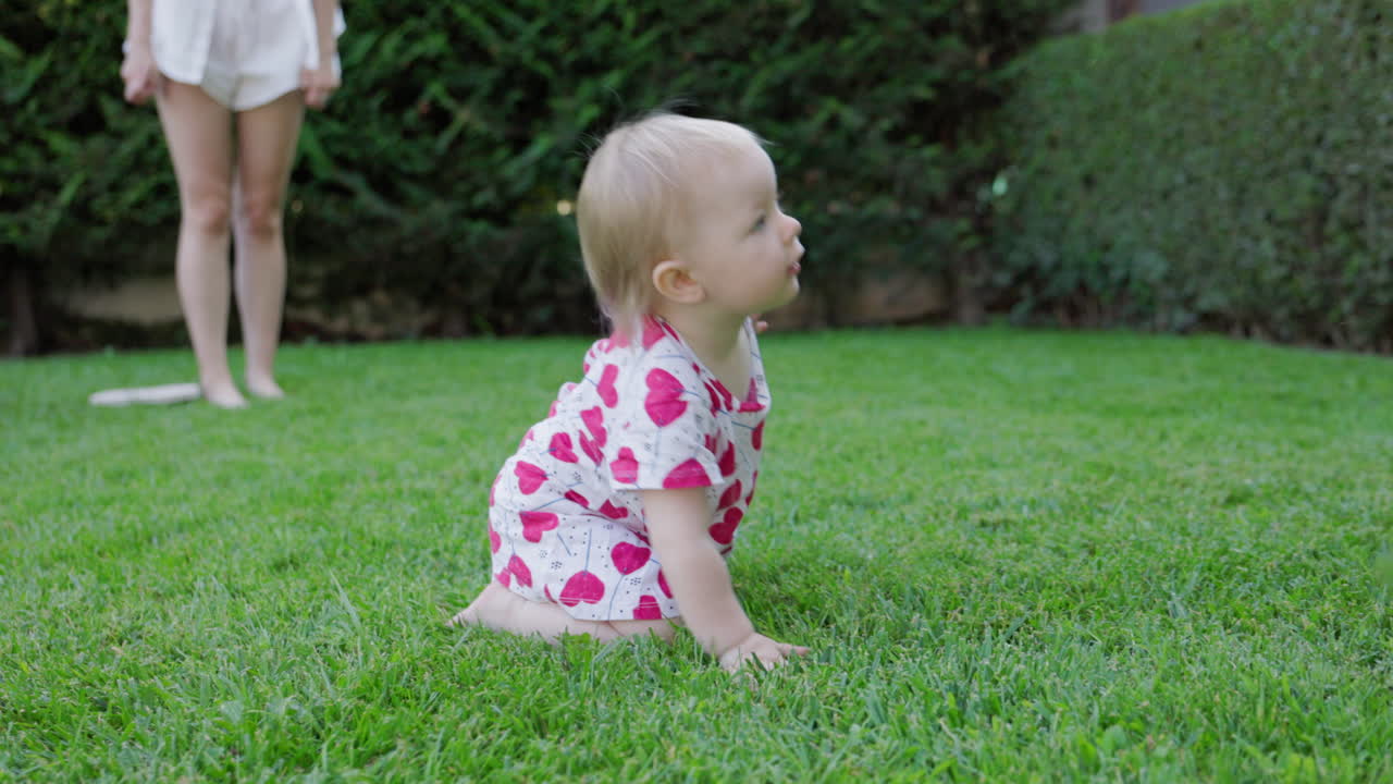 Adorabile bambino che gattona e gioca sull'erba verde in giardino.