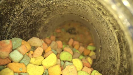 Starting-outside-lid,-pushing-towards-bottom-of-container-of-multi-colored-marshmallow-pieces