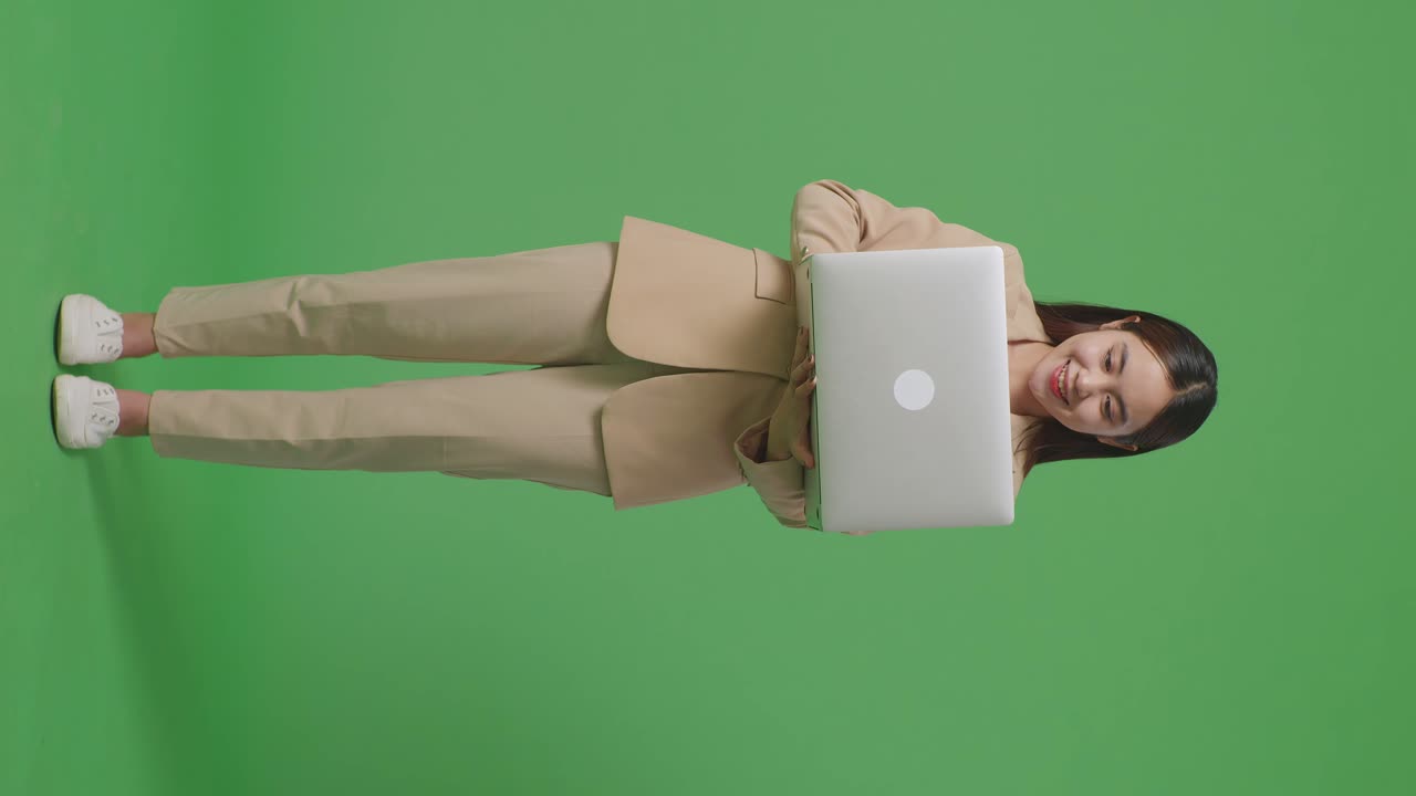 mujer en traje beige sosteniendo una computadora portátil
