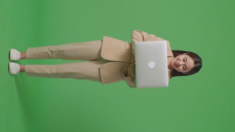 mujer en traje beige sosteniendo una computadora portátil
