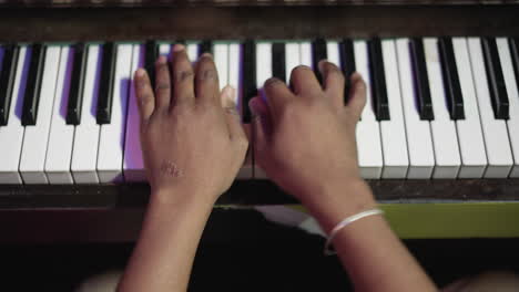 el músico toca una composición en el piano en primer plano en clase. el maestro de música negro interpreta una melodía en un instrumento con teclado en el interior. práctica de tocar