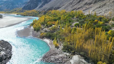 aerial view of a beautiful turquoise river flowing through hills and trees of skardu city in northern pakistan