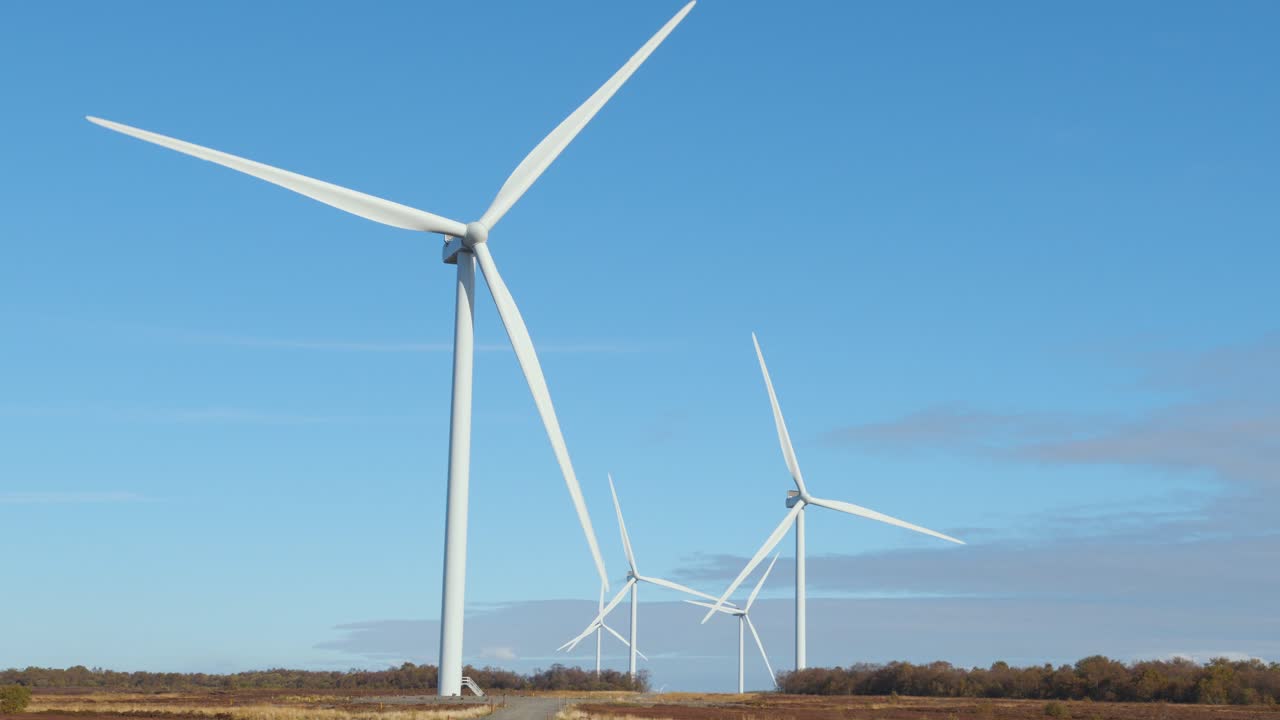 Ripresa statica di cinque turbine eoliche attive che girano in una giornata di sole in Scozia.