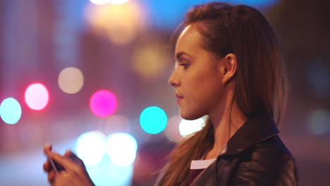 Video-of-city-at-night,-woman-with-smartphone