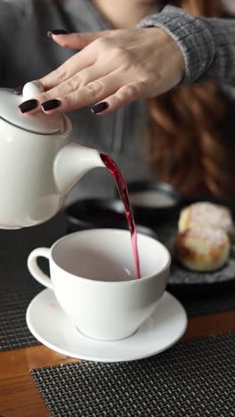 mujer vertiendo té en el desayuno